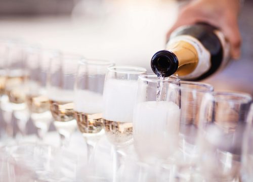 A person pouring champagne into glasses