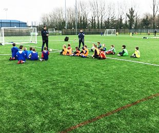 Children watching the coach on the football pitch