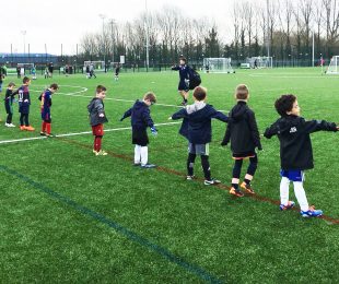 Children doing some warm ups in football camp on the football pitch