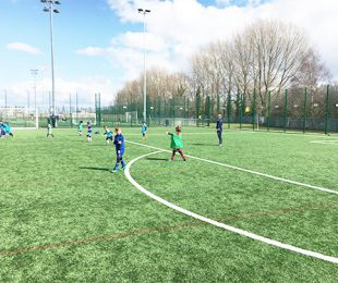 Children playing Football in the sun on a 4k weather pitch