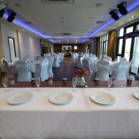 Tables and chairs with plates on the table ready for a wedding