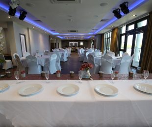 Tables and chairs with plates on the table ready for a wedding