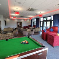 Pool table in lounge area with chairs and sofas